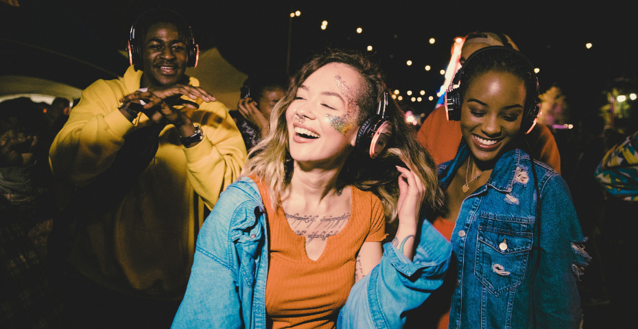 man and two women at silent disco wearing headphones smiling